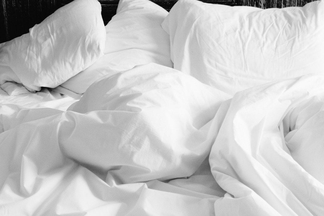 Crisp white bed sheets and pillows in a messy, unmade bed, evoking the comfort of a well-used and cozy sleeping space, ready to be refreshed and cleaned